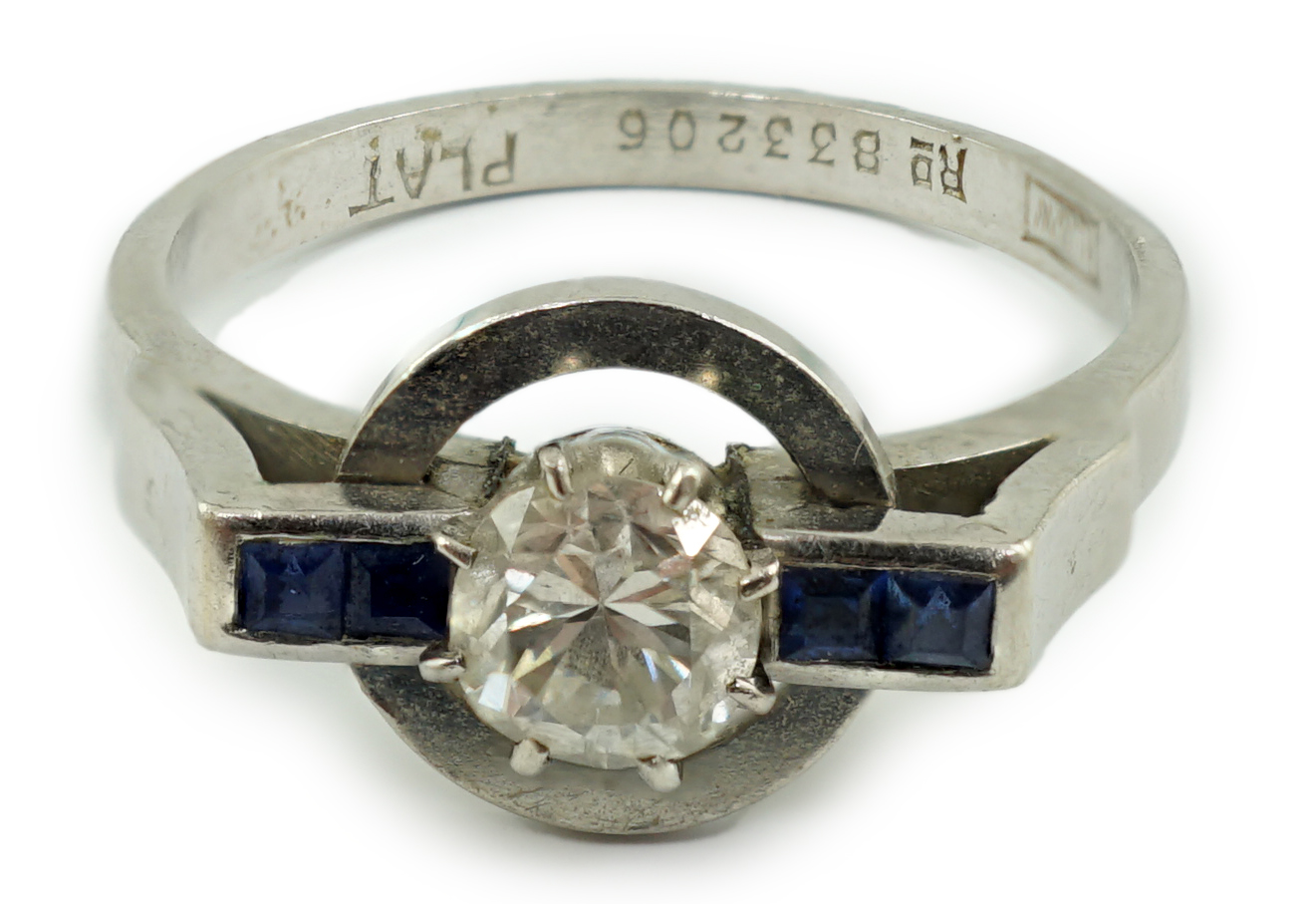 A platinum and single stone diamond set target ring, with four stone square cut sapphire set shoulders